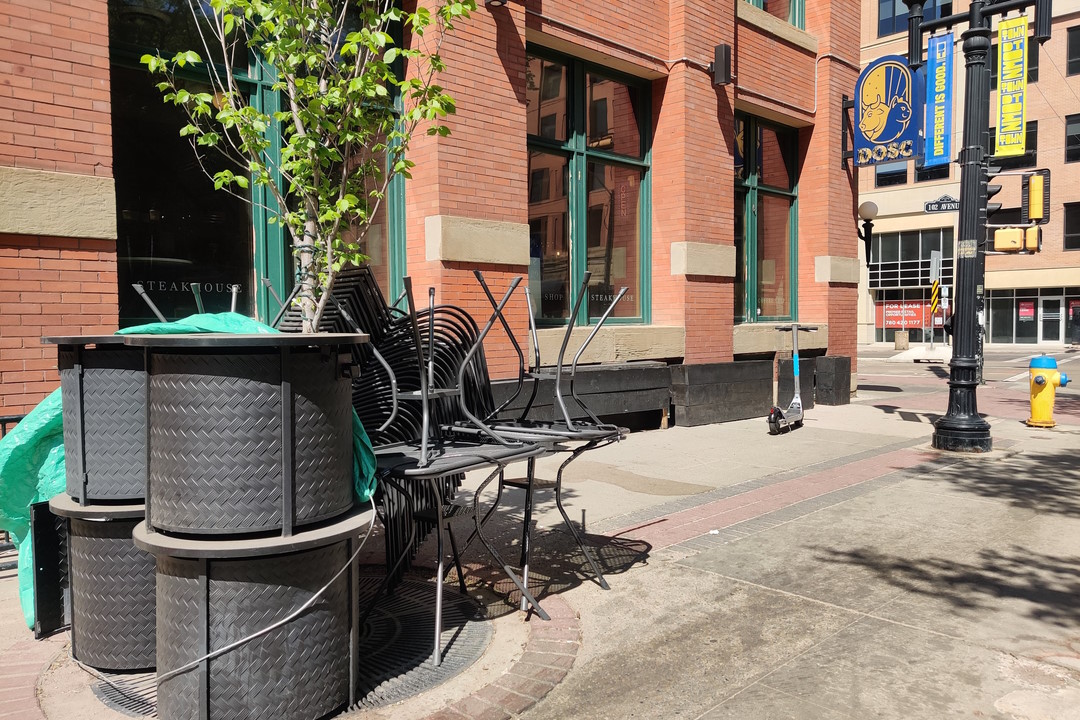 Unused patio furniture piled up outside of a restaurant called DOSC on 104 Street.
