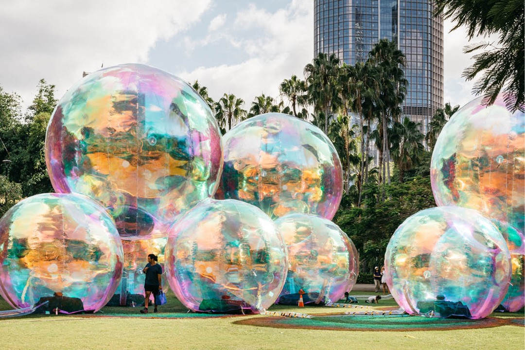 An art installation called Evanescent featuring giant iridescent bubbles that people can walk beside and underneath