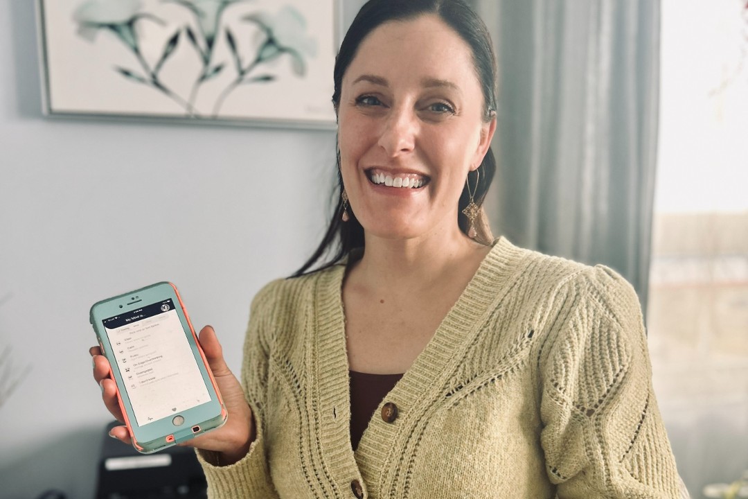 Dóchas Psychological Services founder Kim Long stands in her office while holding her phone with the Lifejacket app open.