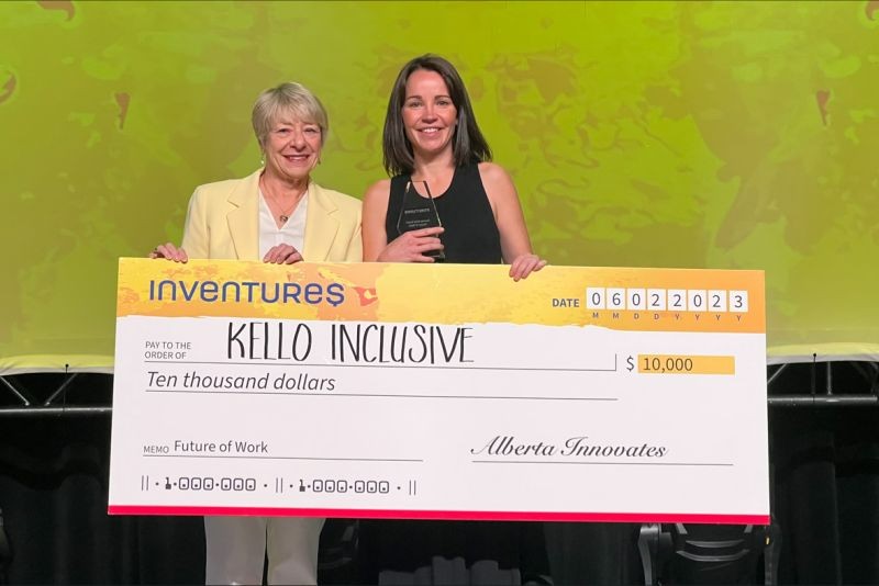 Alberta Innovates CEO Laura Kilcrease and Kello Inclusive's Katie MacMillan hold a giant cheque for $10,000 at the Inventures conference in Calgary.