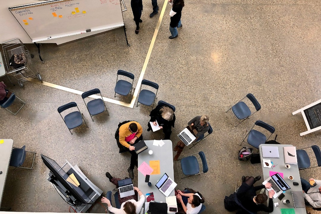A top-down view of a room with people at tables using laptops