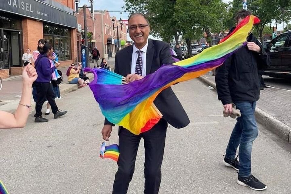 Mayor Amarjeet Sohi waves a rainbow flag on an Edmonton street