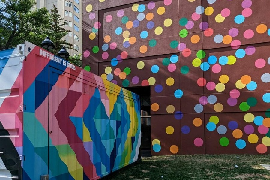 A multi-coloured container with the words "Different is Good" beside the wall of polka dots at Michael Phair Park