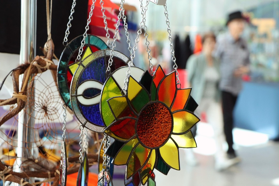 A dreamcatcher and several stained-glass sun catchers hang on a display