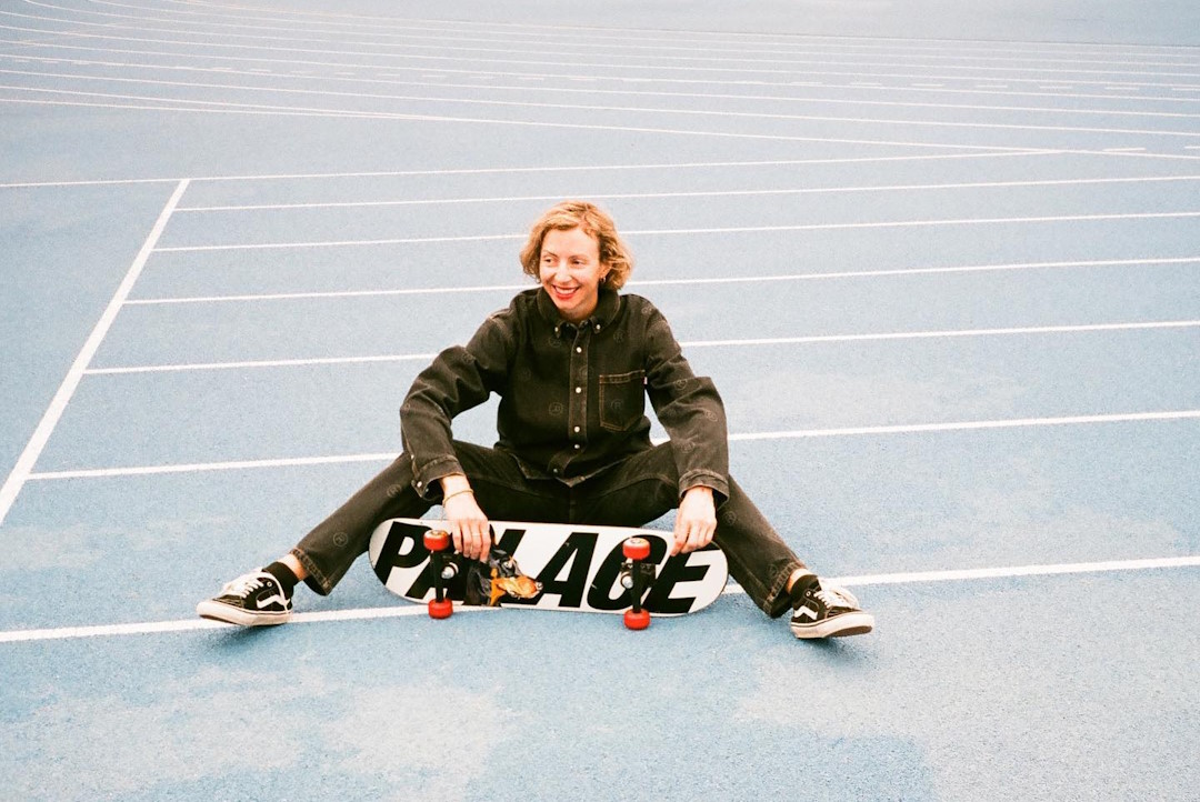 Lexi Pendzich seated on the ground holding a skateboard in front of her