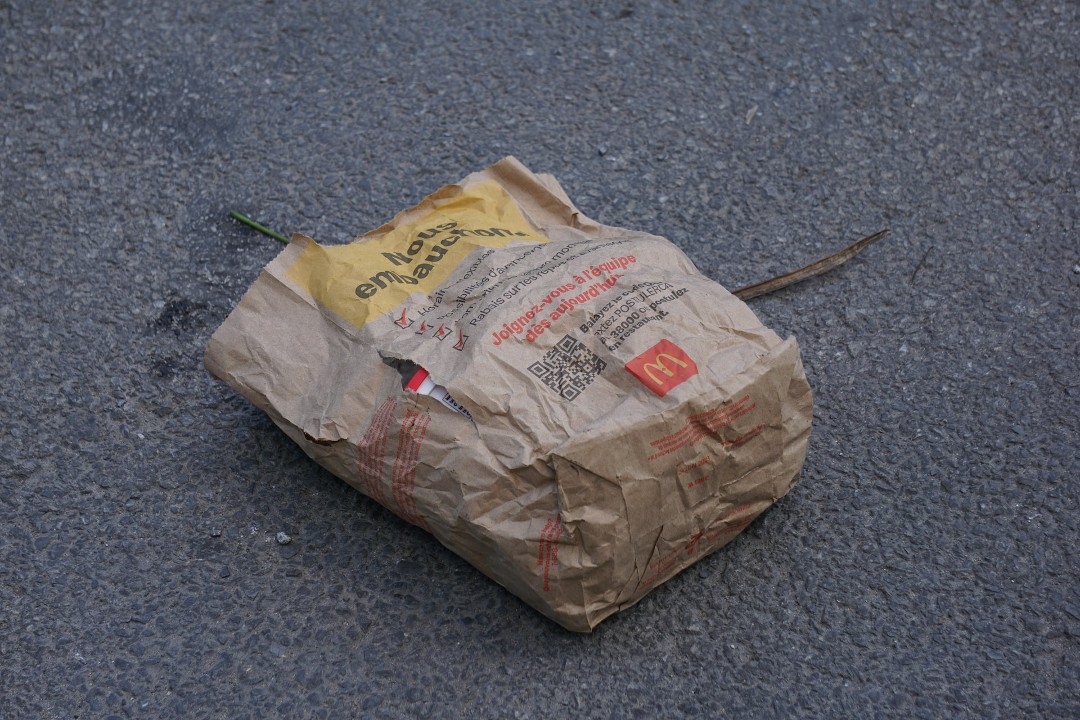 A wrinkled and torn paper McDonald's bag discarded in the street