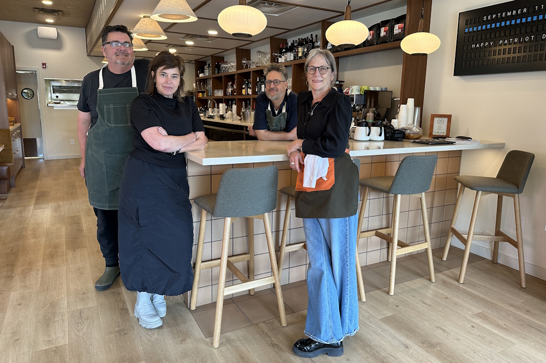 Two couples stand around a counter at Happy and Olive