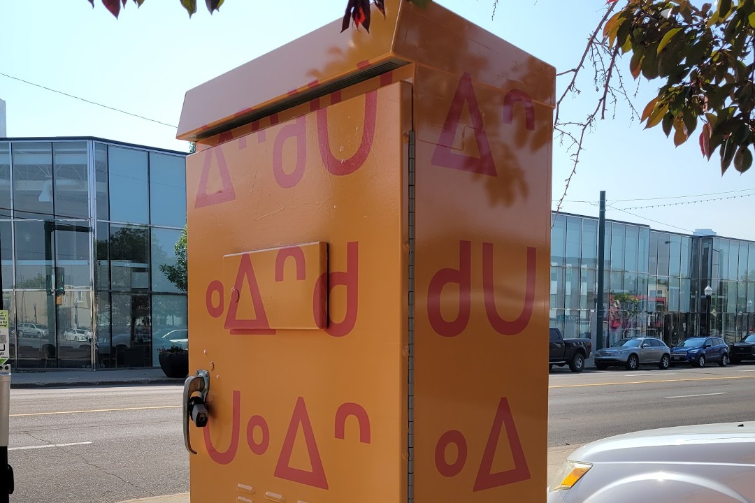 Traffic control box on a downtown street with a design featuring Cree syllabics.