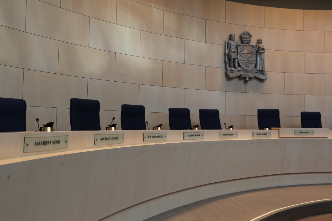 A photo from 2013 of the city hall council chambers, showing empty desks for councillors without glass partitions between them.