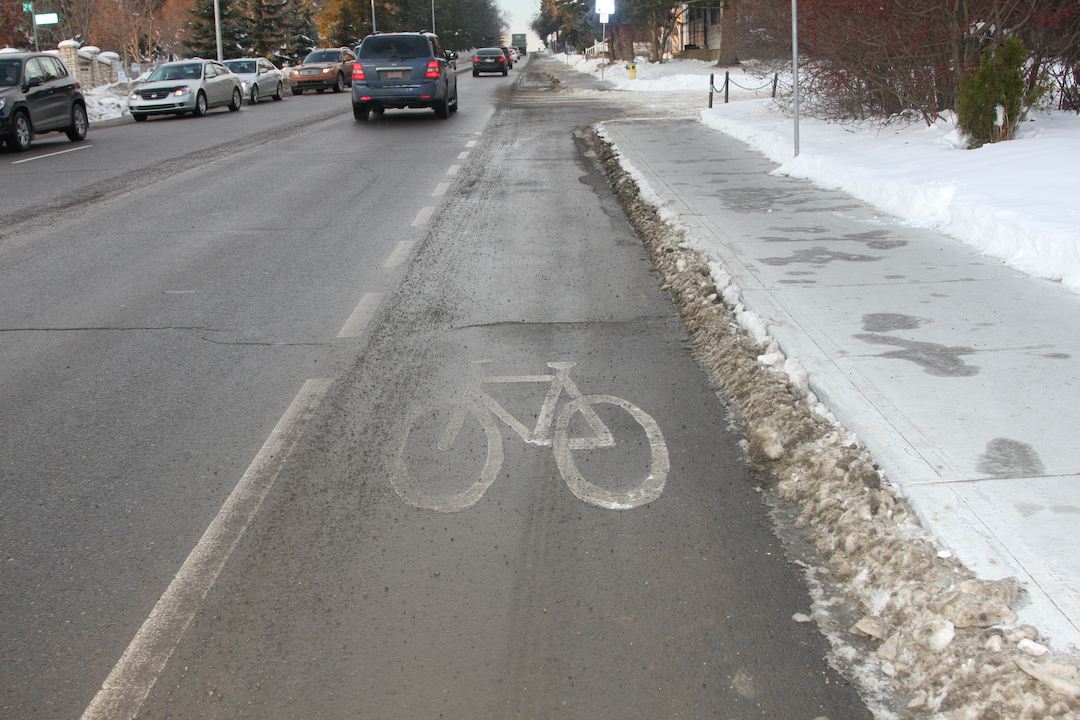 A painted bike lane alongside a road in winter.