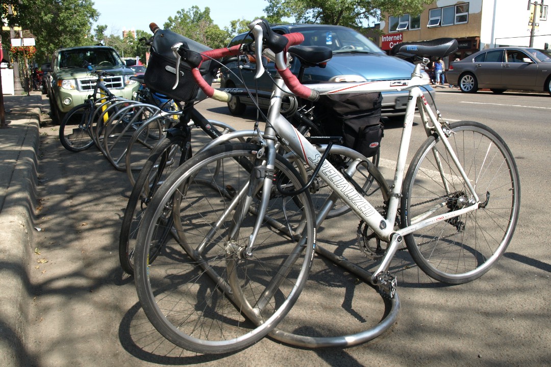 A bicycle is locked with other bicycles at a bike rack on a street in Edmonton.