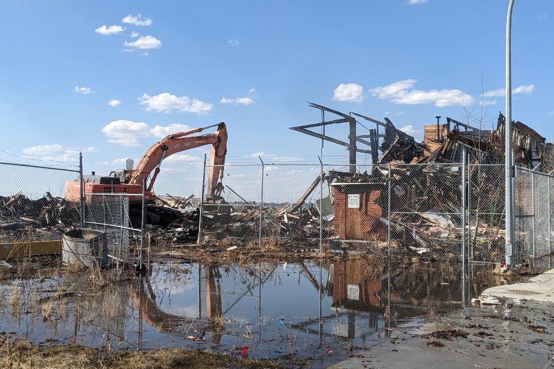 An excavator digs through the remnants of a building that has burned down