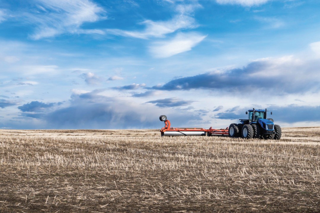 A tractor in a dry-looking field.