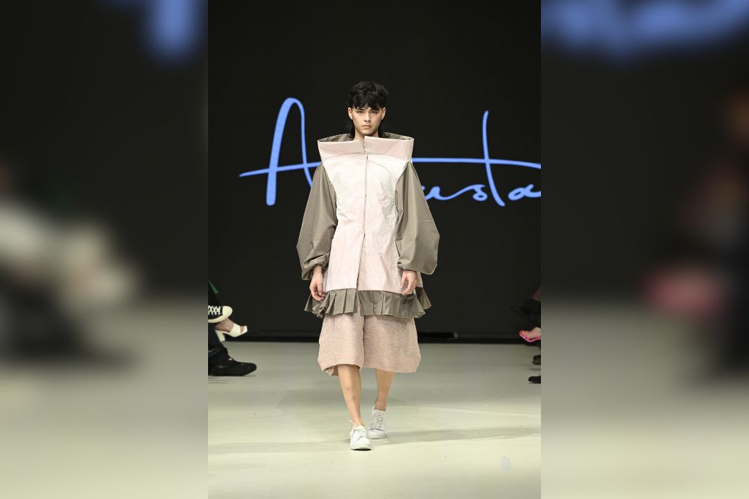 A model walks on a runway wearing Augusta designs.