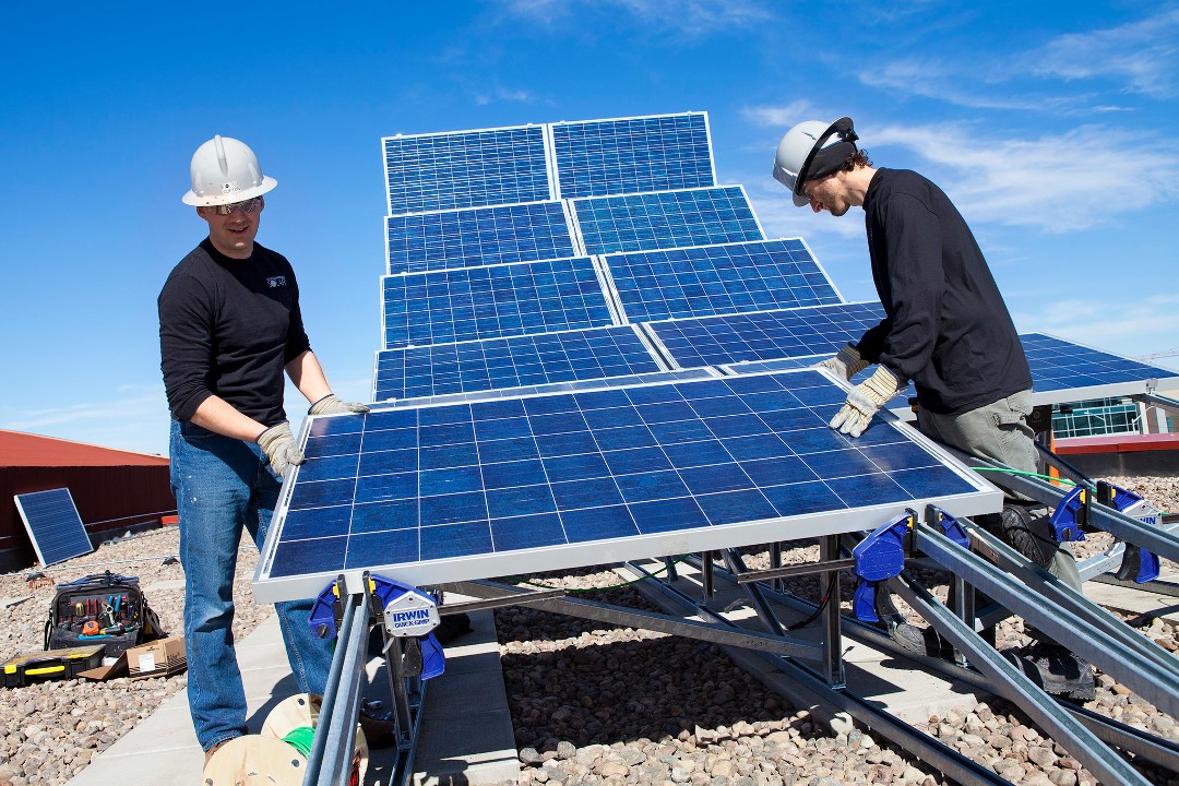 People install solar panels on a roof