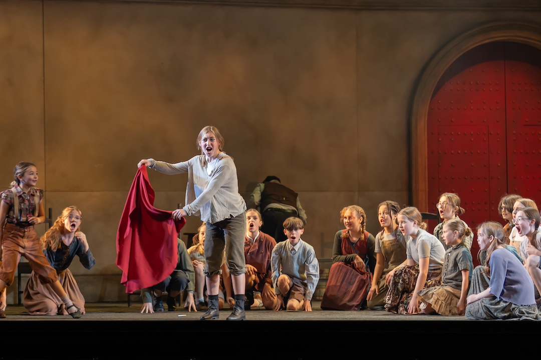 Young people in costumes perform on stage