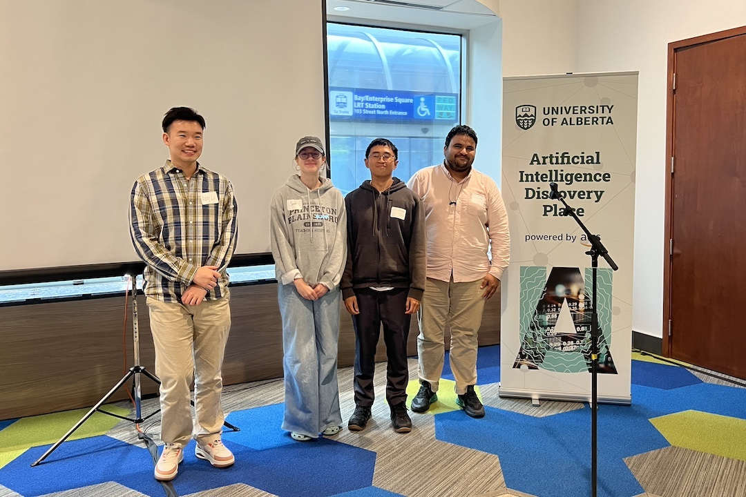 Four people stand in front of a sign that reads "Artificial Intelligence Discovery Place"