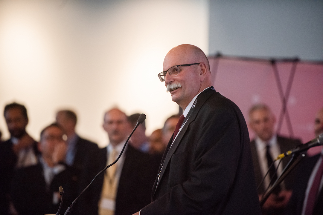 A person in profile stands at a podium.