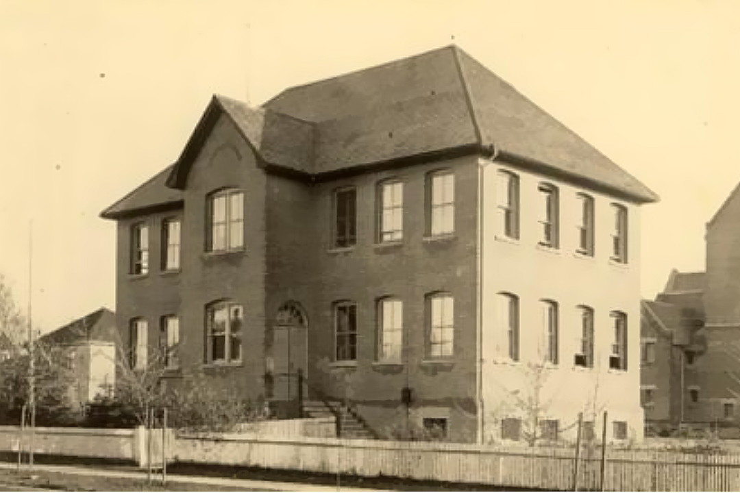 Yellowed archival photo of a two-story brick school