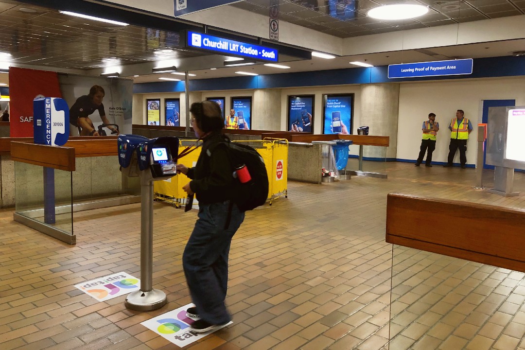 A person taps their Arc card at Churchill LRT station.