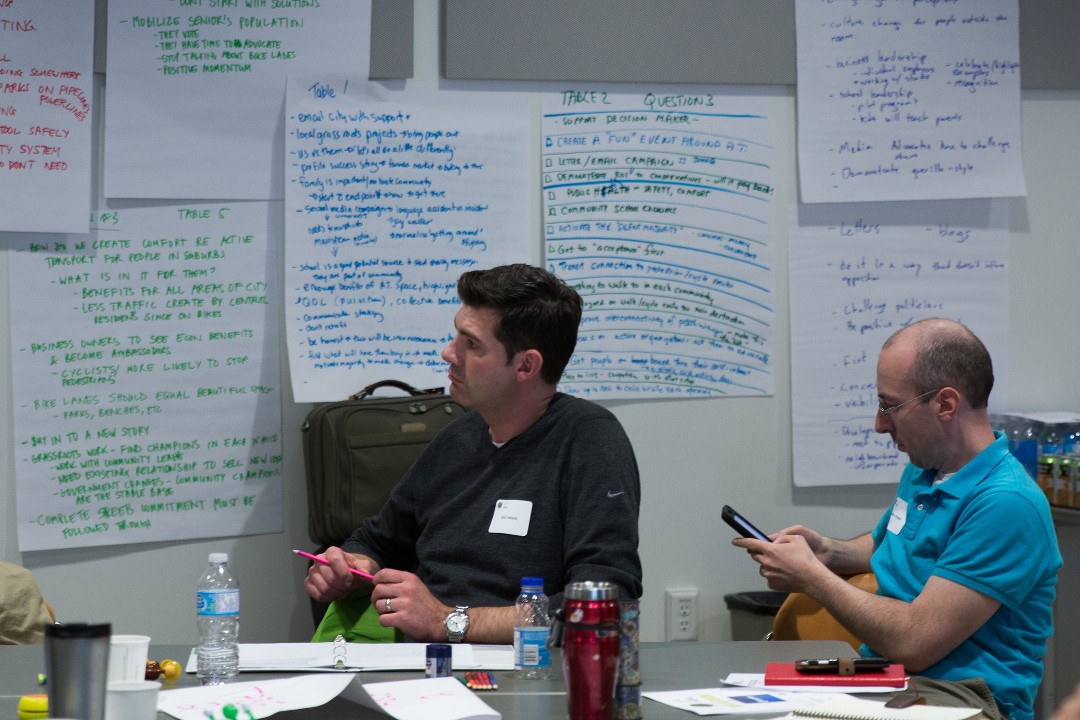 A picture of two people in front of large pieces of paper with notes written on them