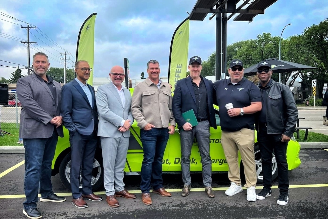 A group of people poses in front of a green car