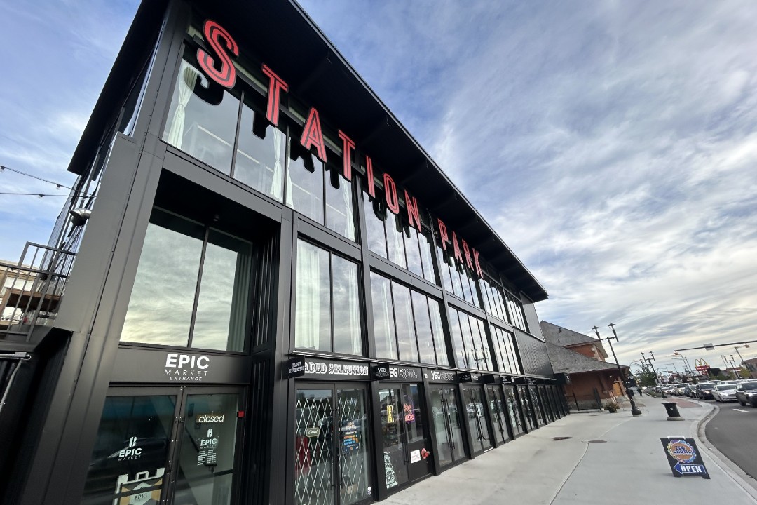 A row of shops in shipping containers sit beneath a sign that reads "Station Park".