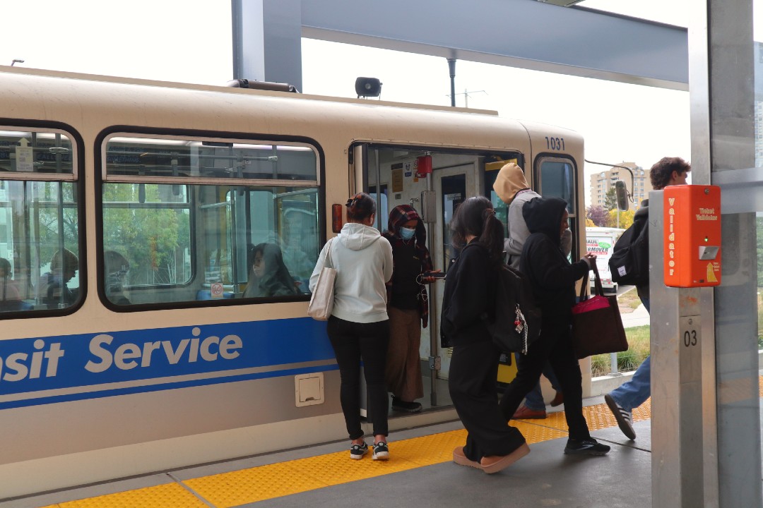 Riders enter and exit an LRT vehicle at Stadium station.