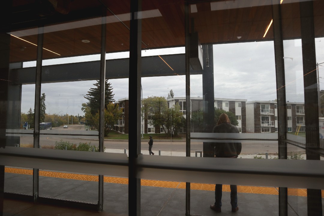 The view from the platform on Stadium Station, showing nearby apartments, a sidewalk, and the ravine.