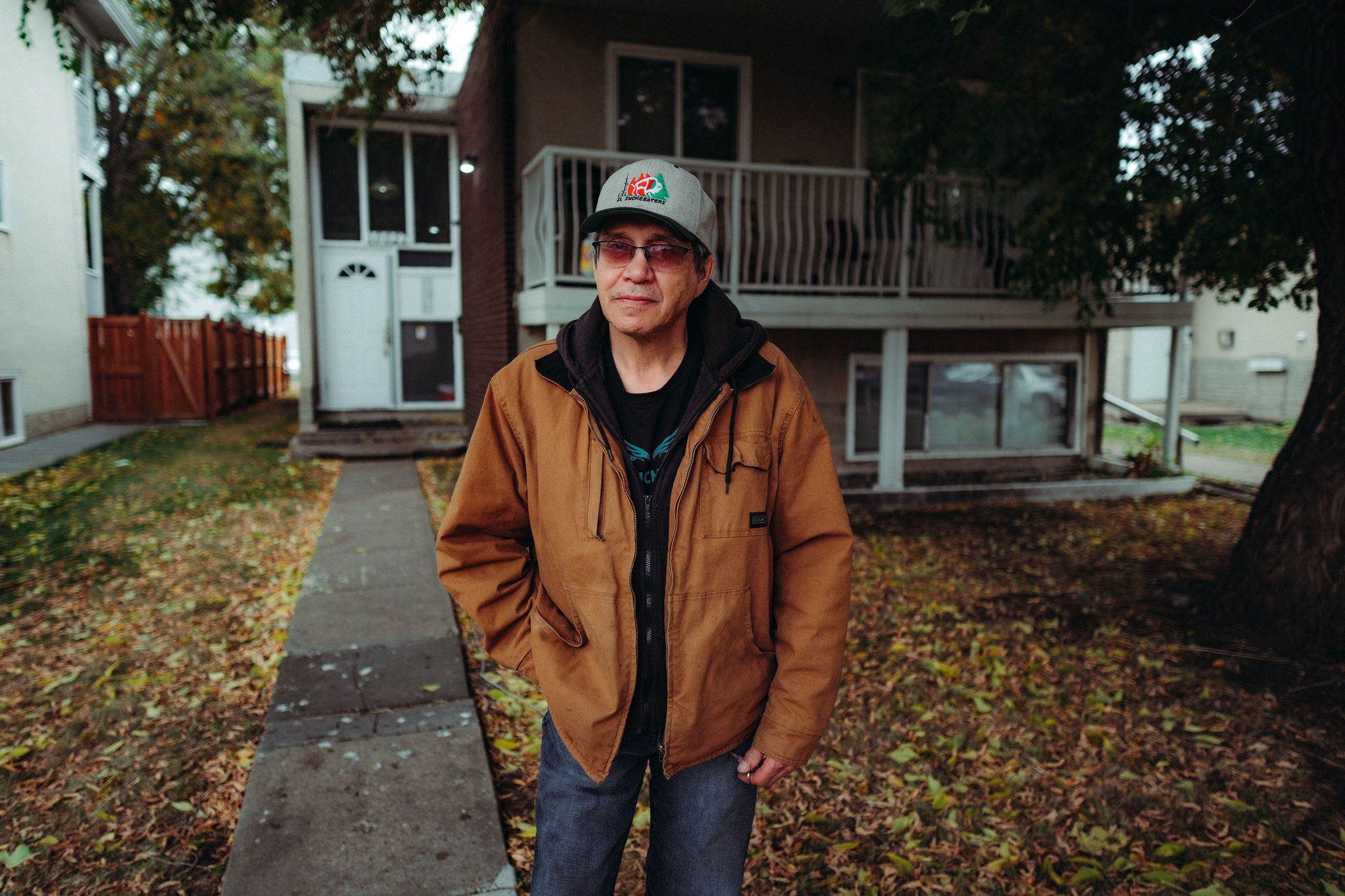 A man stands in front of a low-rise apartment building.