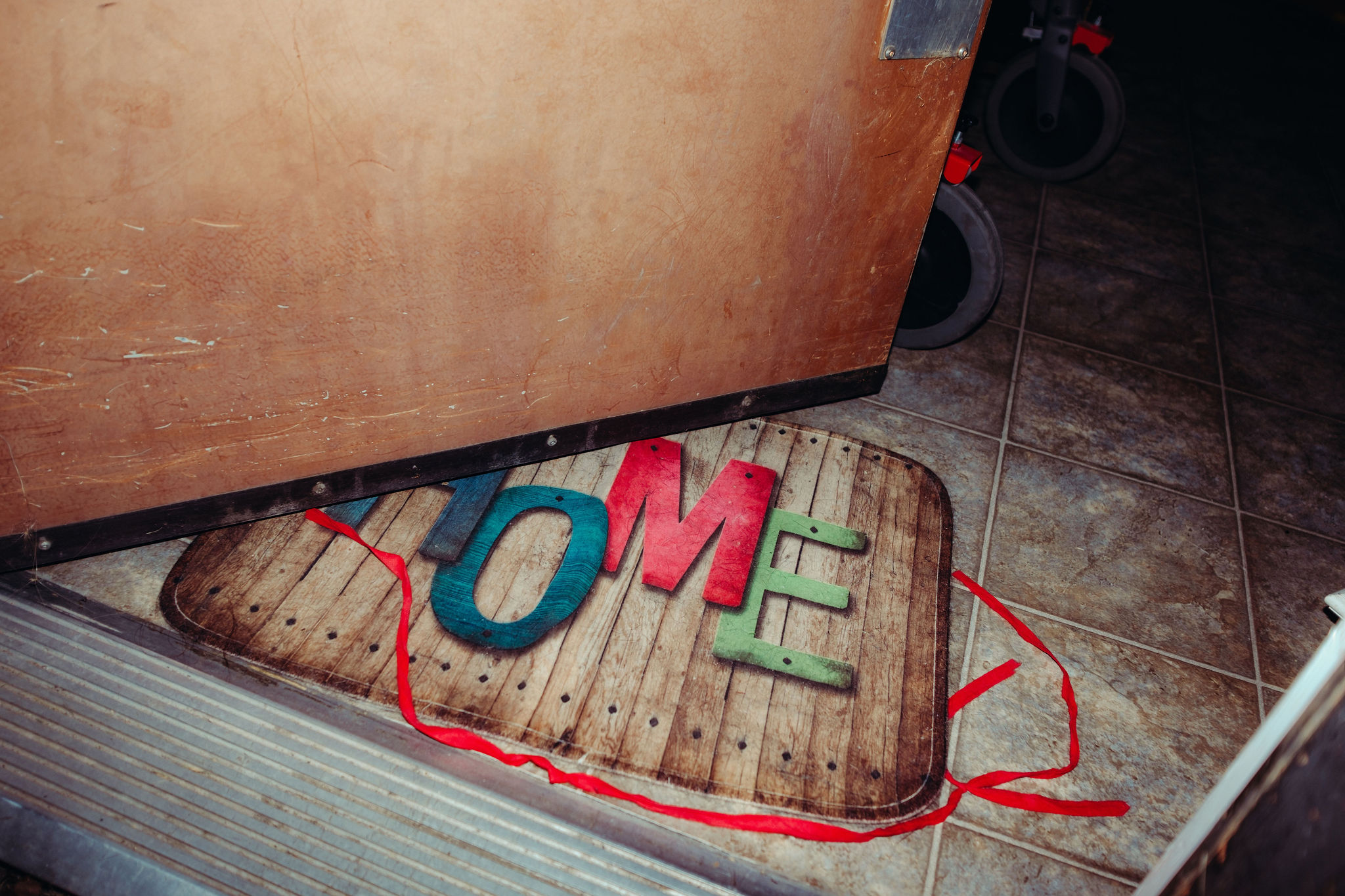 A photo of a colourful doormat that has the word "Home" on it.