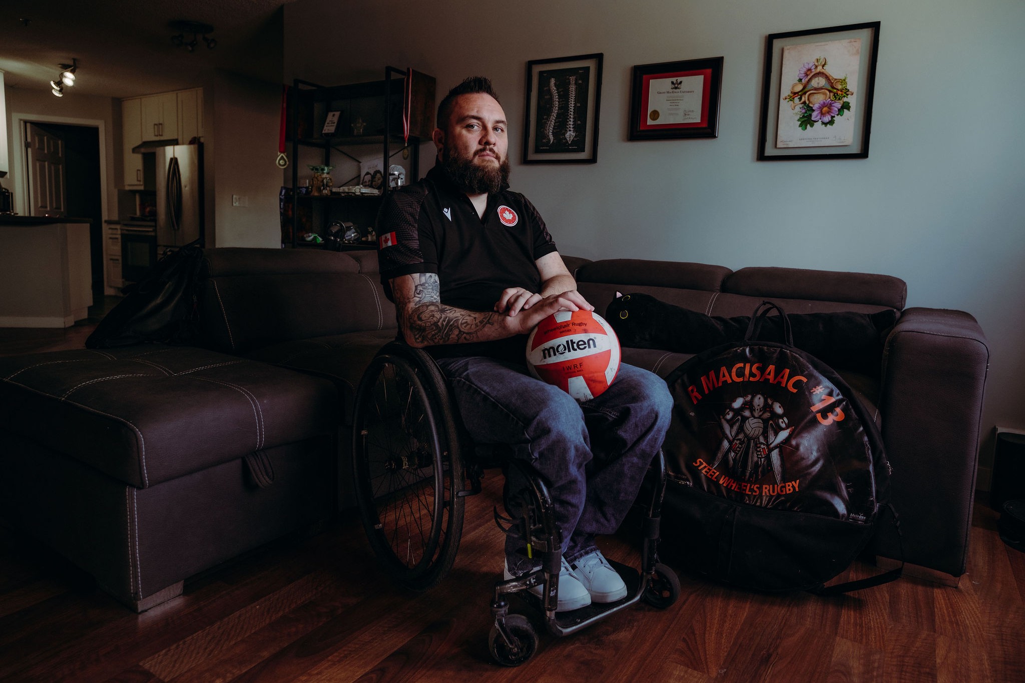 A man holds a rugby ball and looks at the camera.