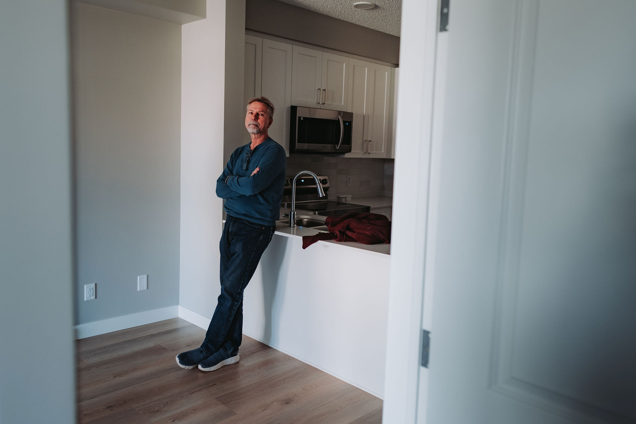 A man leans against a kitchen island in an empty home.