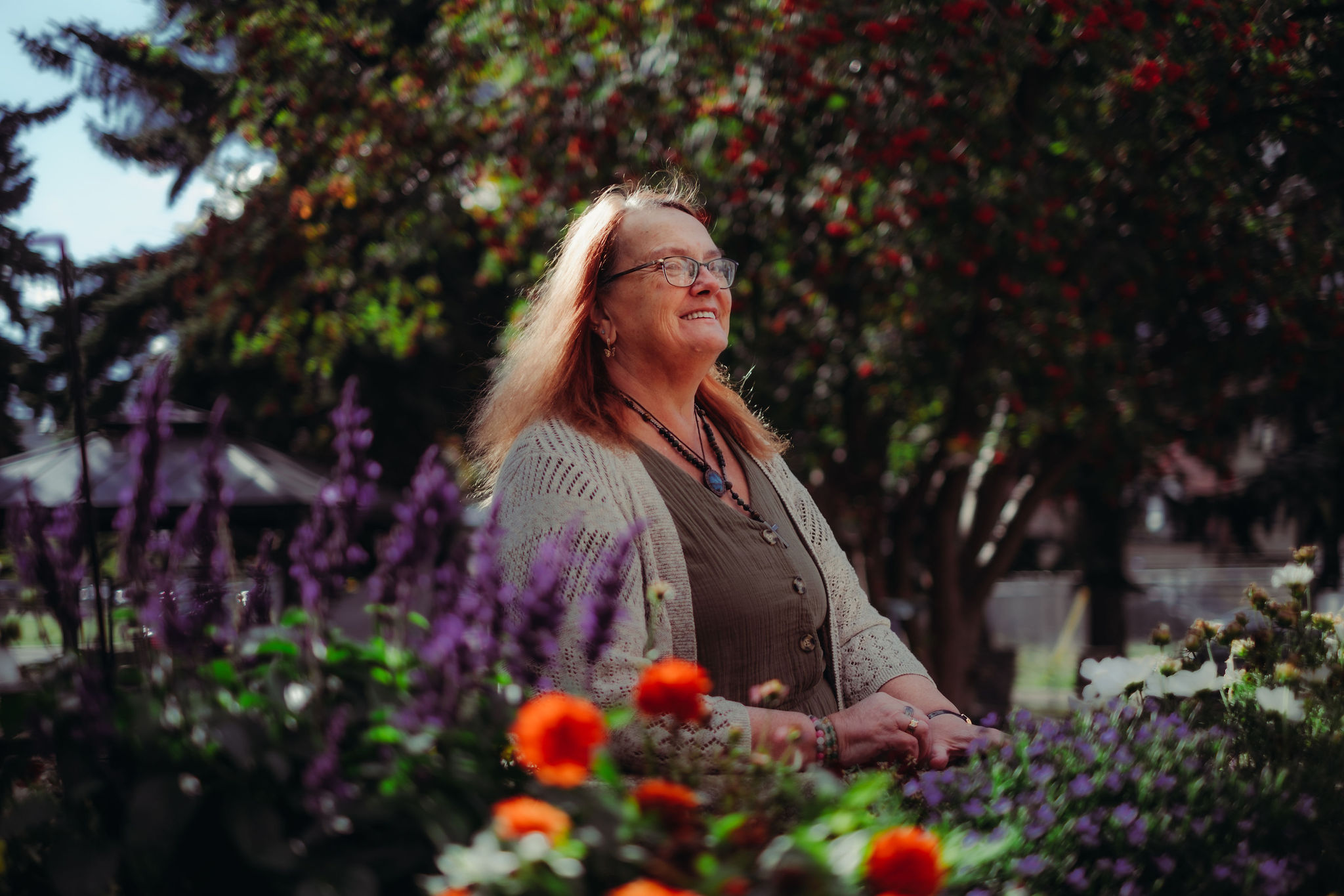 A woman smiles surrounded by flowers.