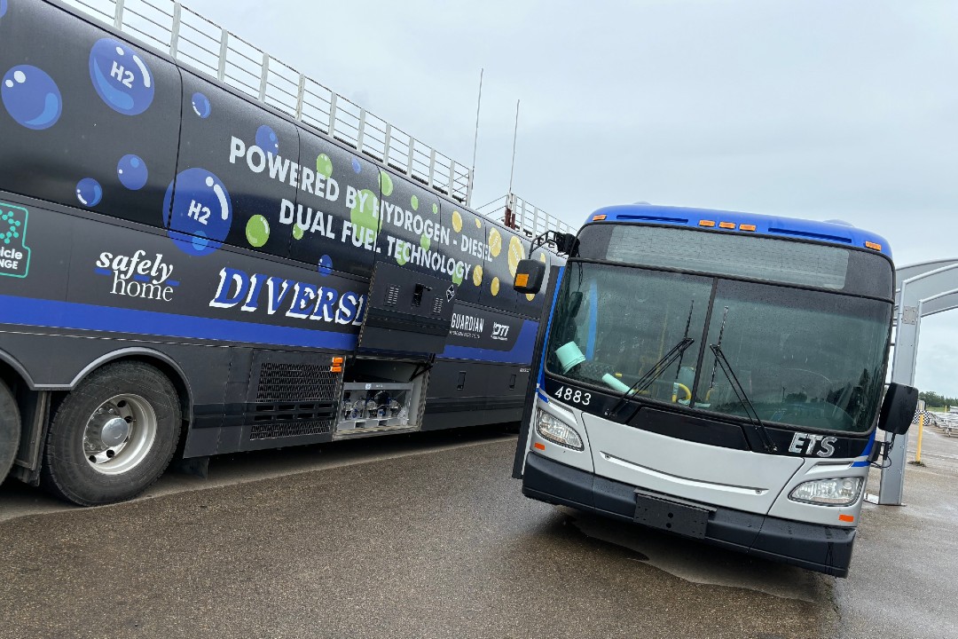 A Diesel Tech Industries coach and an Edmonton Transit Service bus on a rainy stretch of pavement.