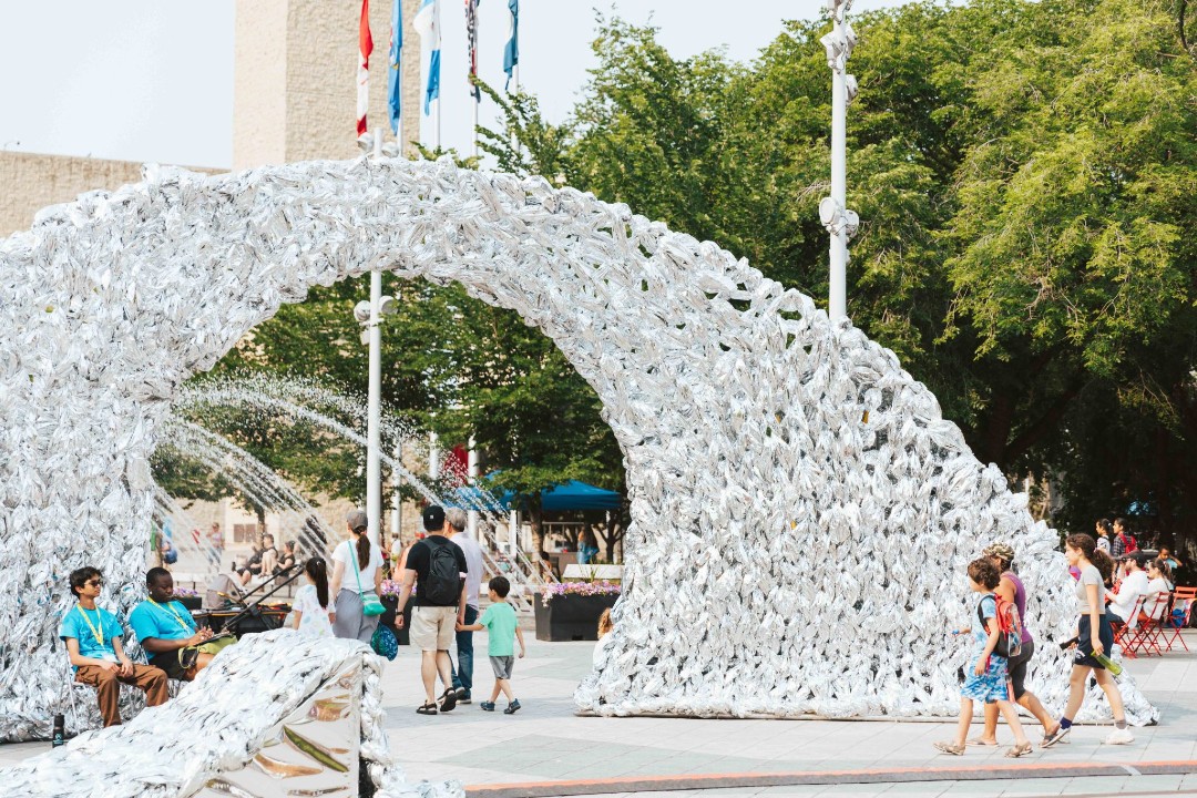 An artwork of a white archway at Churchill Square in Edmonton stands in front of flags.