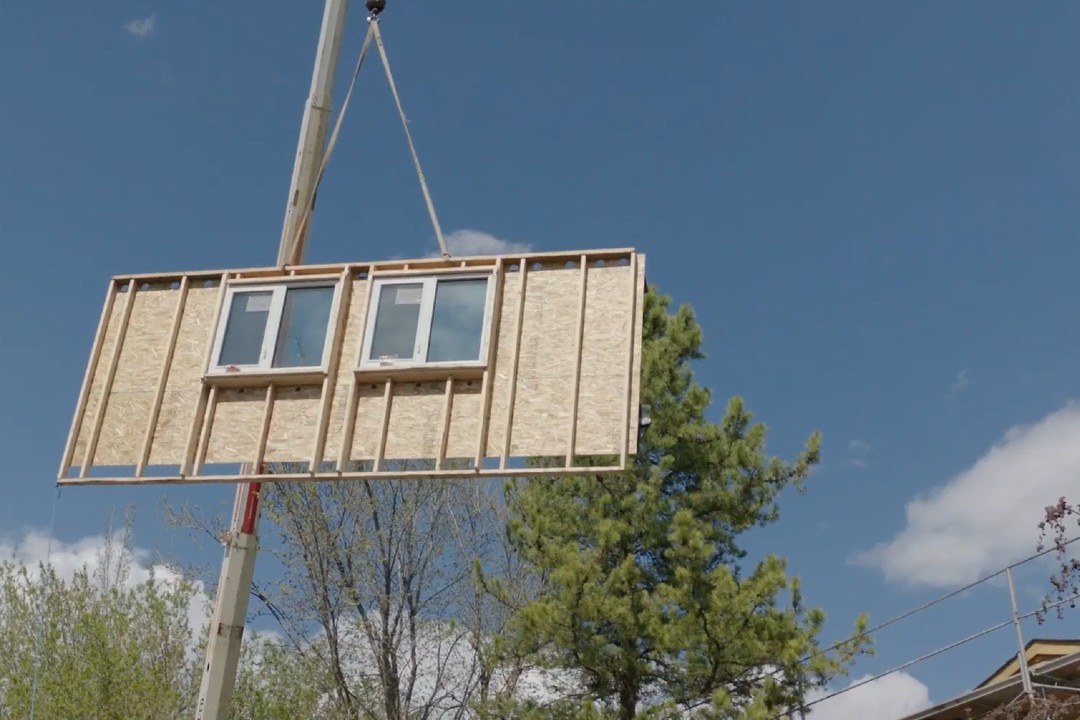 A panel for the exterior of a home to improve its energy efficiency is suspended from a crane.