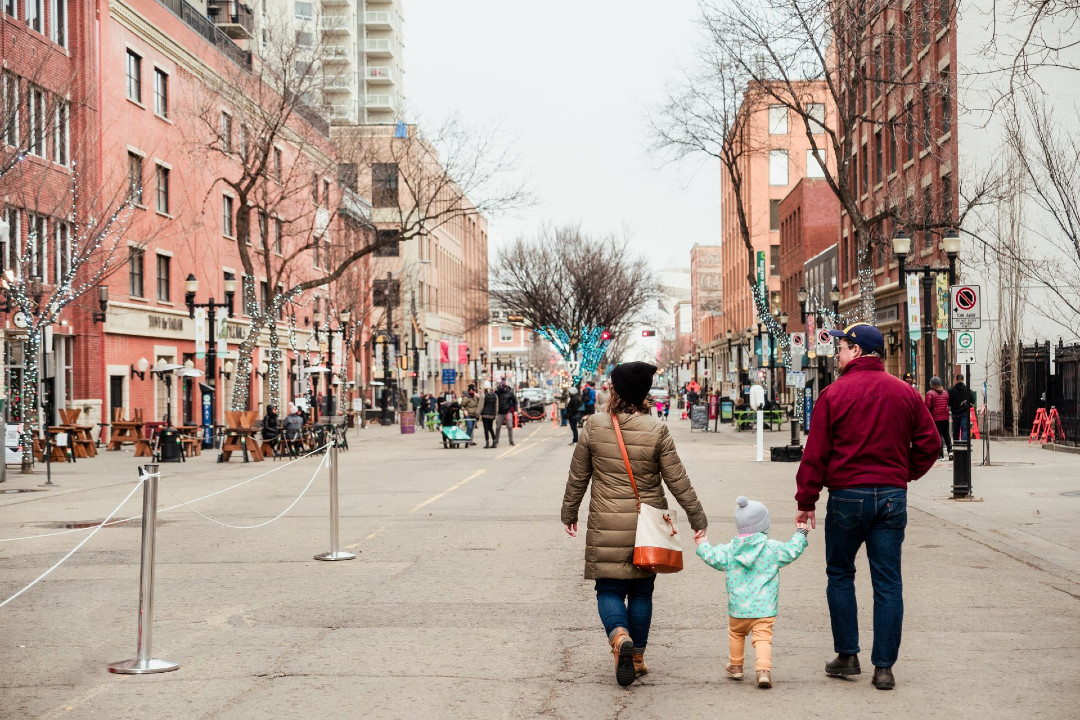 A view down 104 Street in downtown Edmonton, with a young couple with a child in the foreground