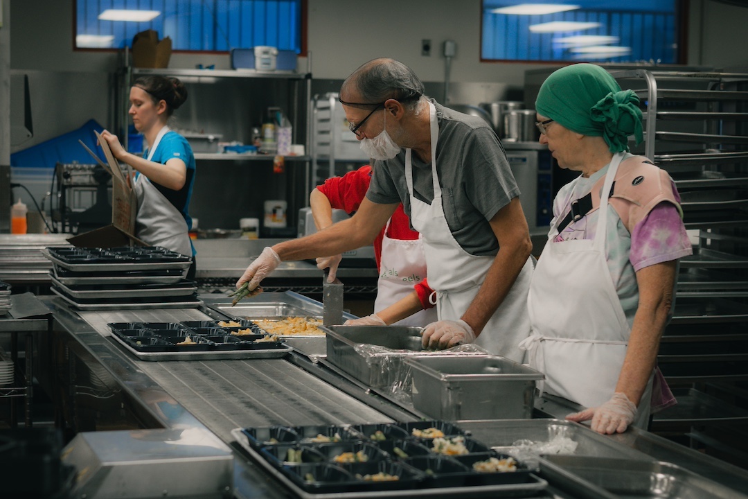 People work in an industrial kitchen, packaging food