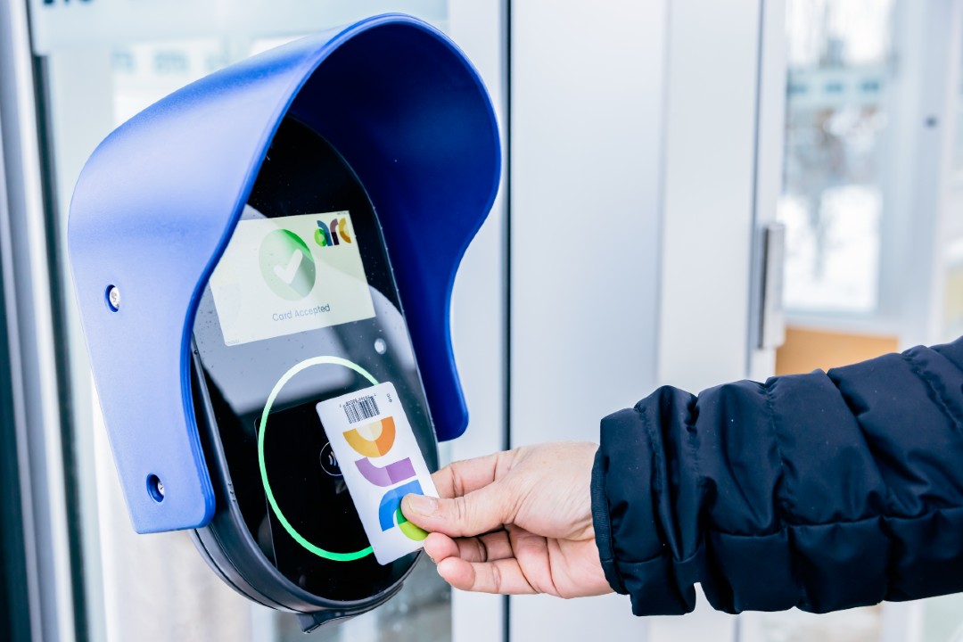 A hand holding an Arc card makes contact with a fare validator at an Edmonton Transit Service LRT station.