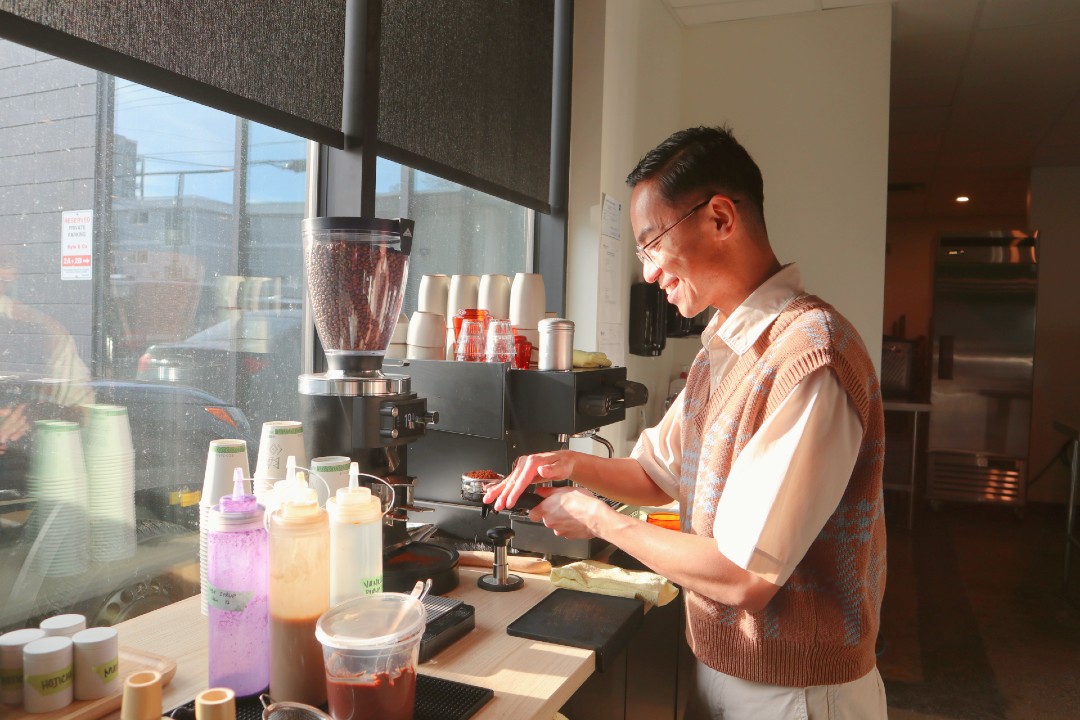 A person prepares a coffee at an espresso machine.