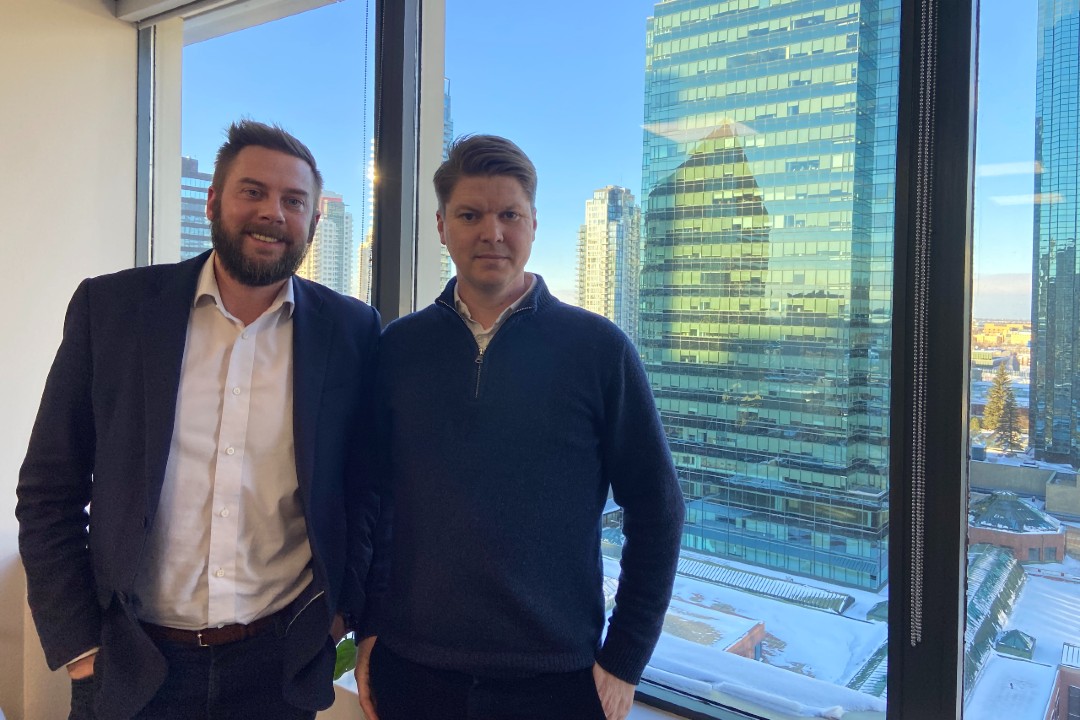 Varme Energy Inc.'s Sean Collins and Andreas Grav Karlsen pose in front of a window overlooking downtown Edmonton.