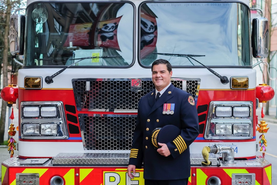 A fire chief poses in front of a fire truck.