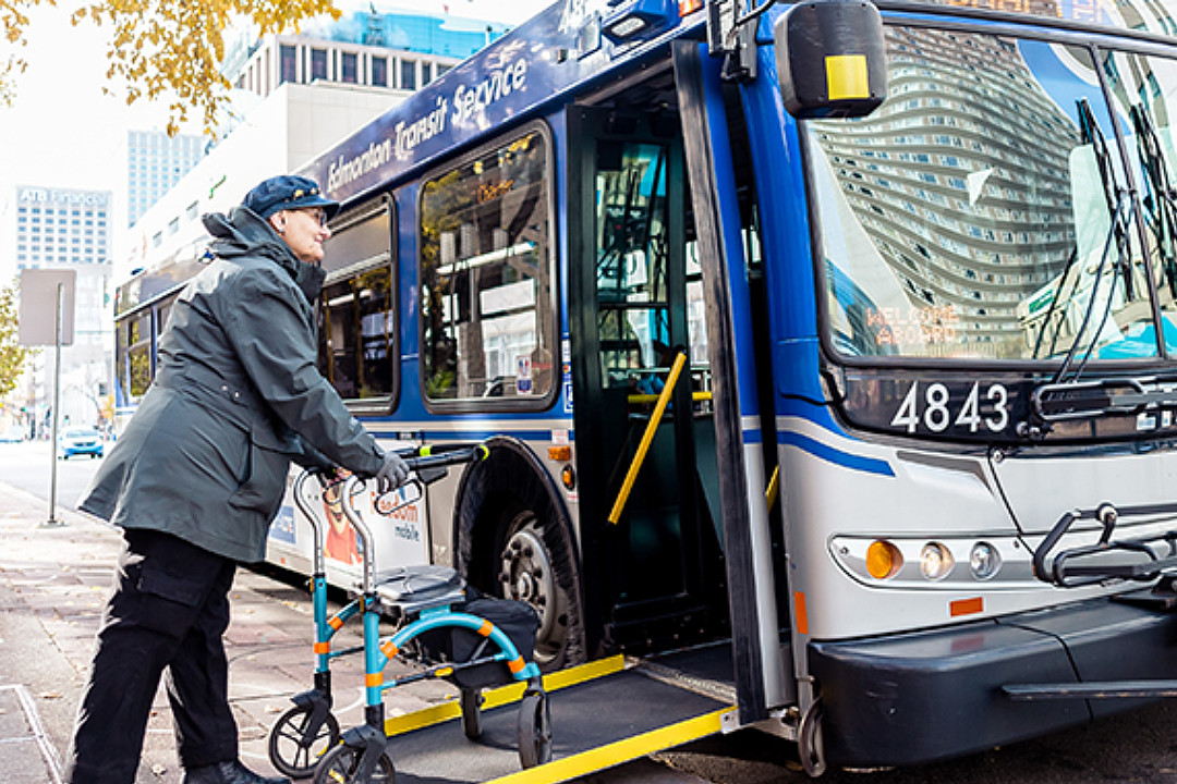 Person with a walker boarding an Edmonton Transit Service bus via an accessibility ramp