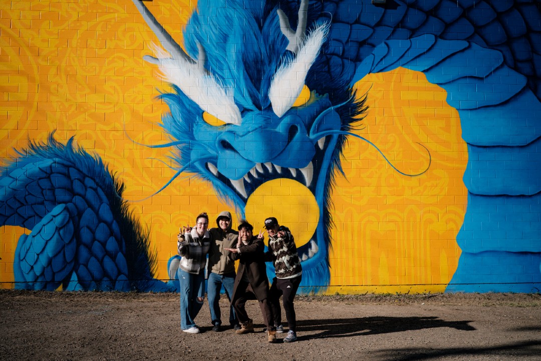 Documentary about Chinatown mural to screen at inaugural Edmonton edition of FascinAsian A group of people pose in front of a mural depicting a dragon.