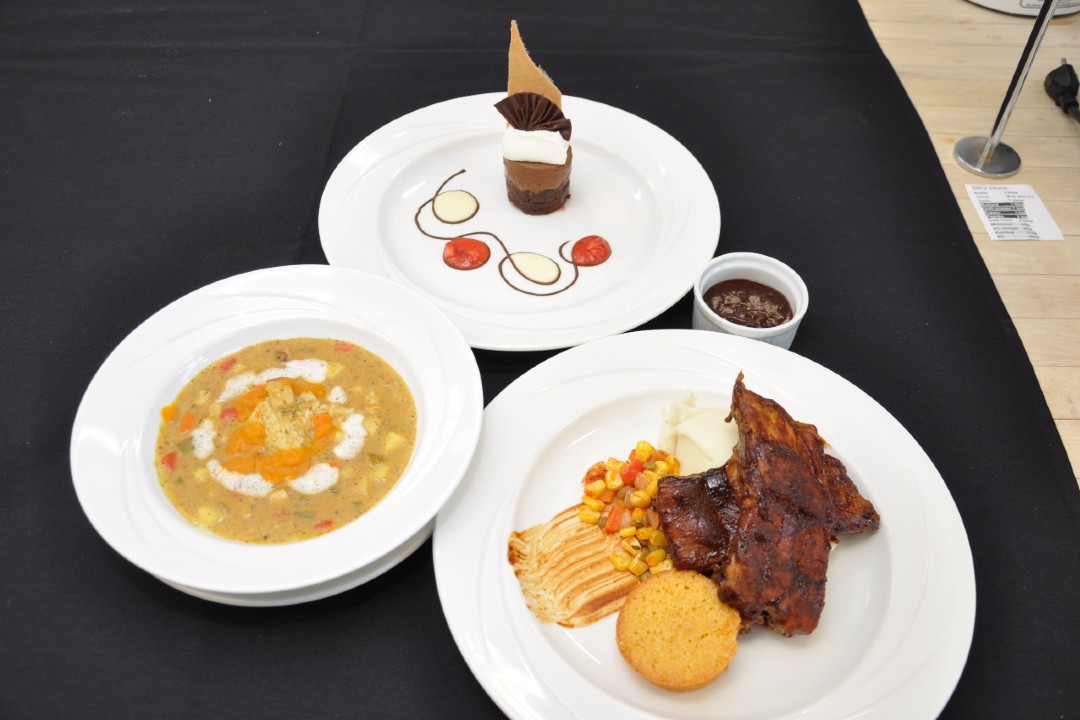 Three plates and a ramekin holding a meal prepared by a competitor of the High School Culinary Challenge.