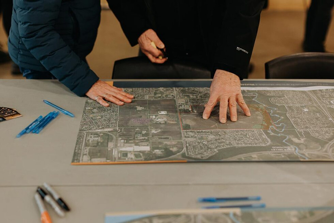 Two people standing at a table, considering a printed map of a proposed area structure plan
