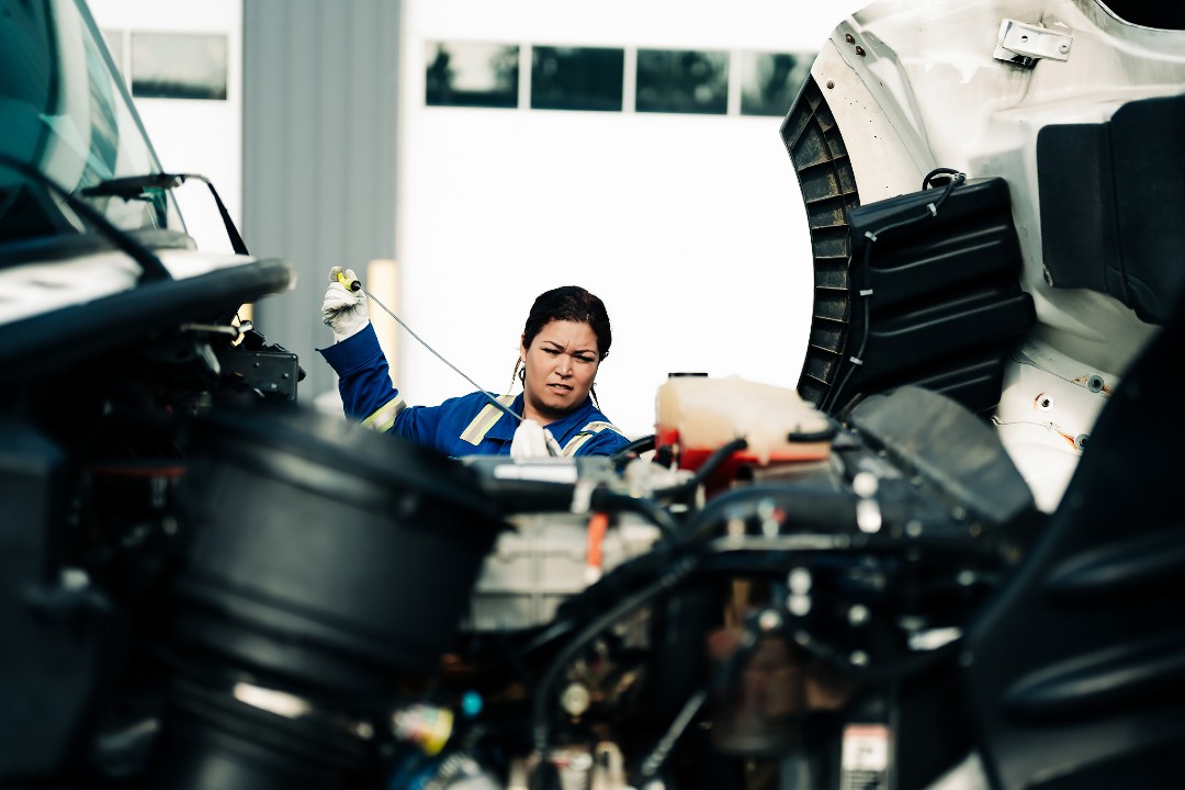 Women Building Futures expands to Ontario A woman wearing coveralls works on machinery.
