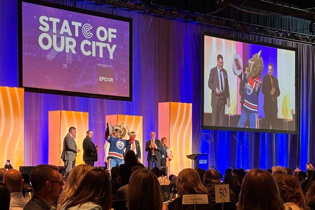 Noted: State of city event, traffic troubles, police commission calm Standing people surround Hunter the Lynx, the mascot of the Edmonton Oilers, on a stage.