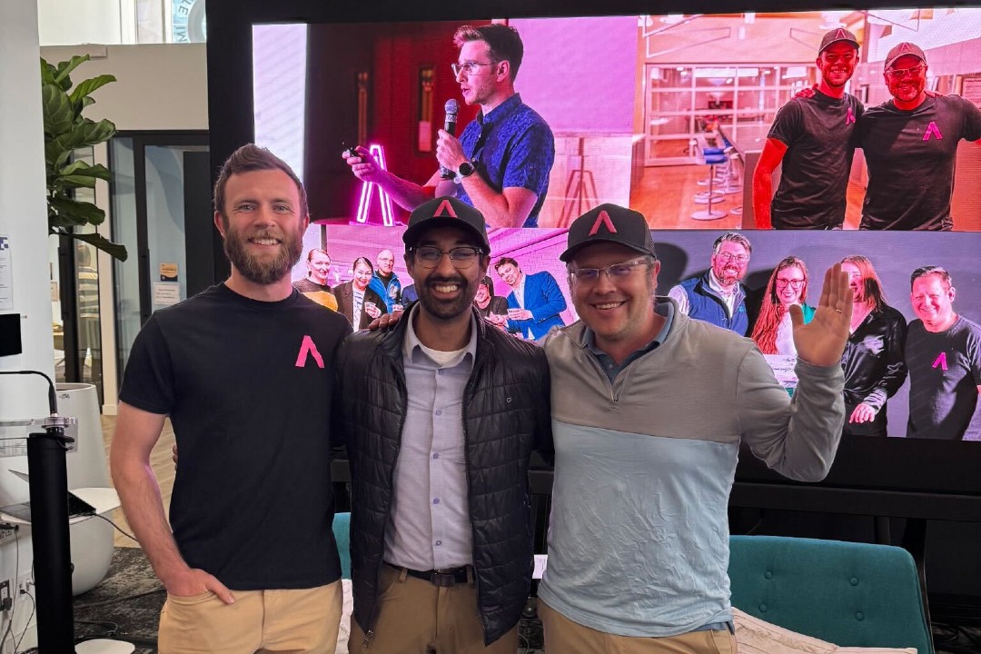 Startup TNT hires executive director to allow co-founders to iterate and build community Three men wearing Startup TNT merchandise pose in front of a TV.